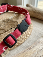 Red dog collar with black buckle on a woven mat